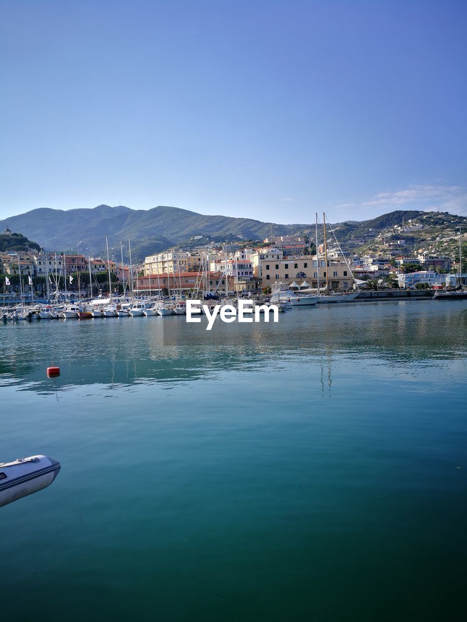 Boats moored at harbor against clear sky