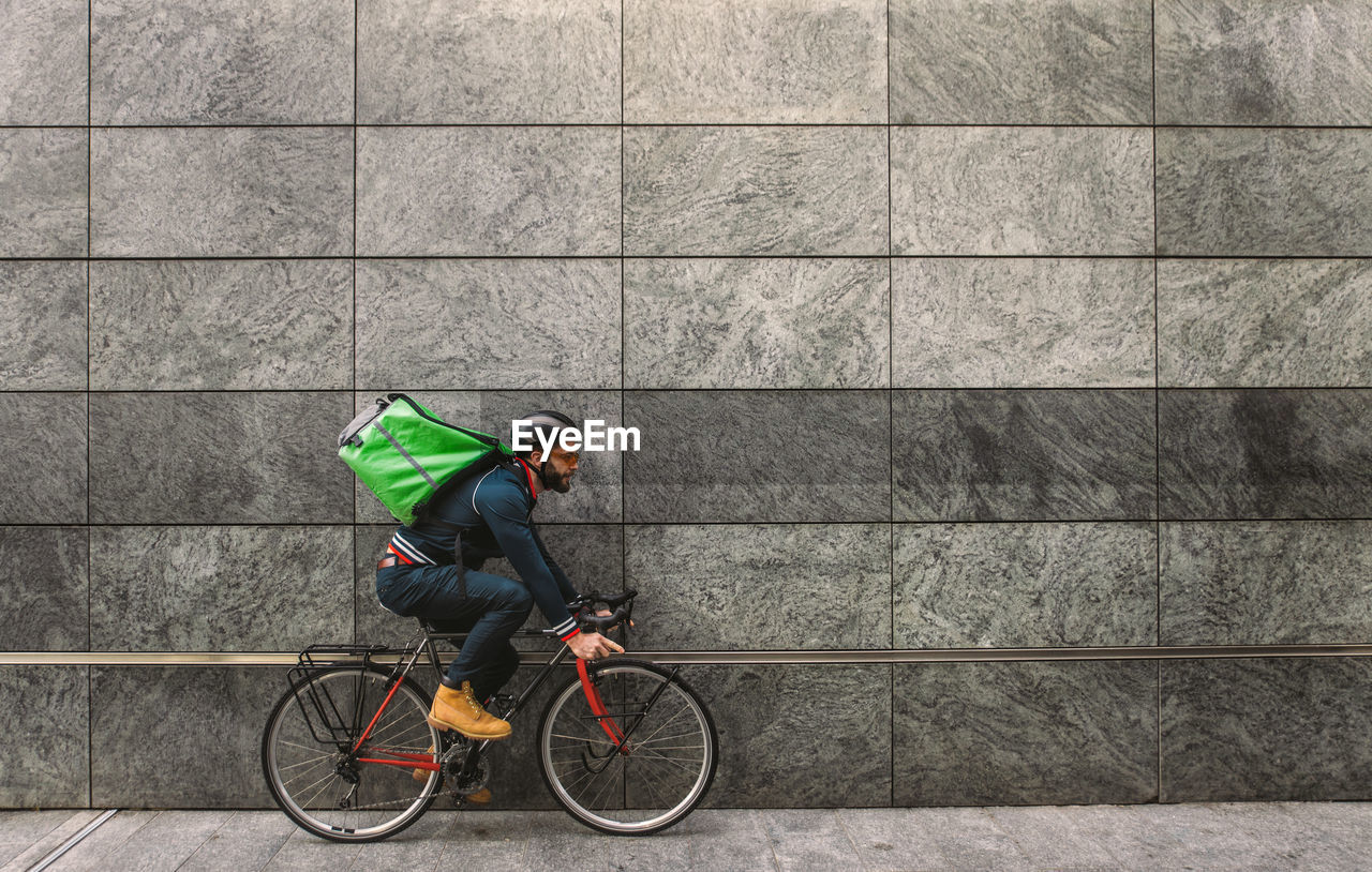 MAN RIDING BICYCLE BY WALL