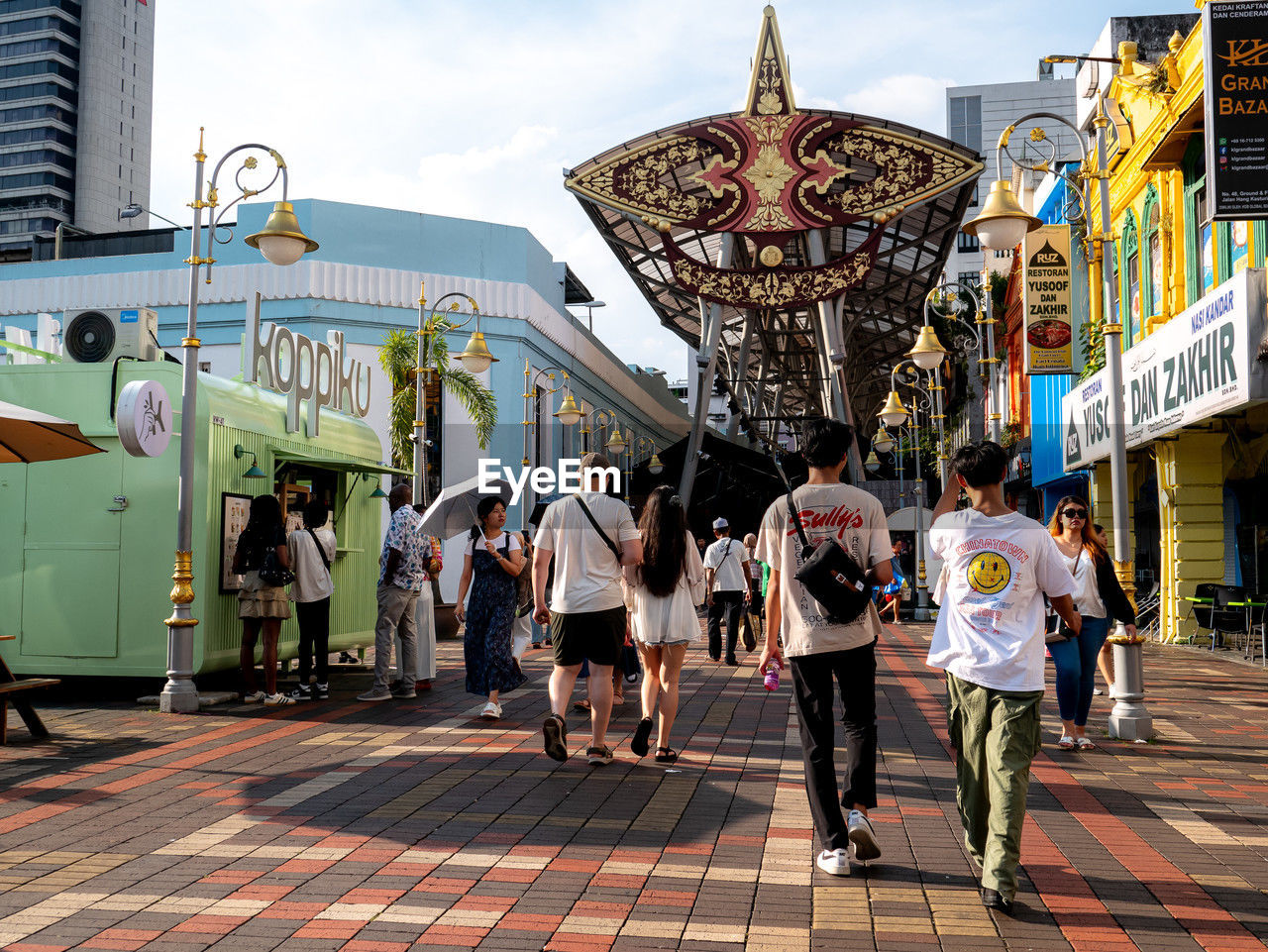 architecture, group of people, crowd, city, building exterior, road, street, built structure, adult, men, large group of people, tourism, women, sky, city life, arts culture and entertainment, walking, amusement park, person, full length, travel destinations, day, travel, nature, outdoors, urban area, leisure activity, lifestyles