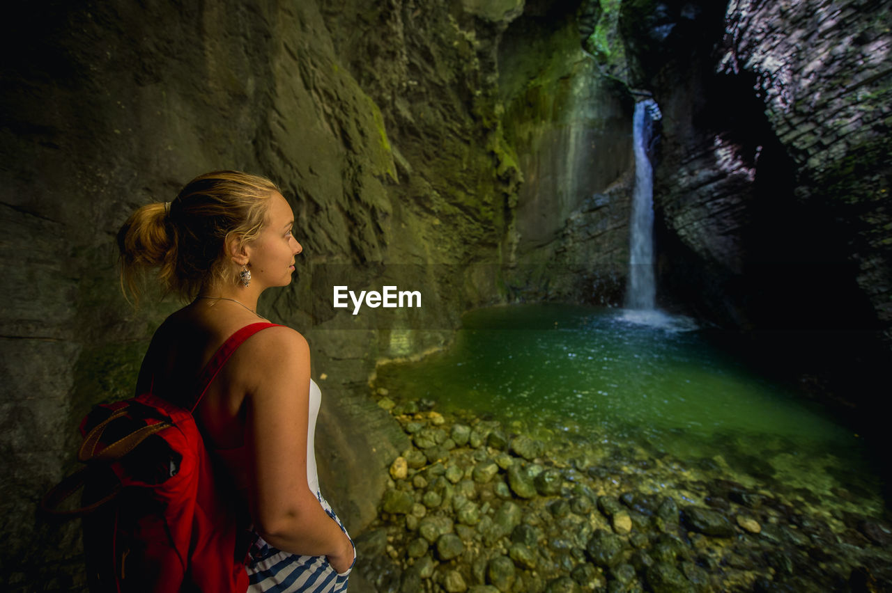Young woman looking at waterfall in cave