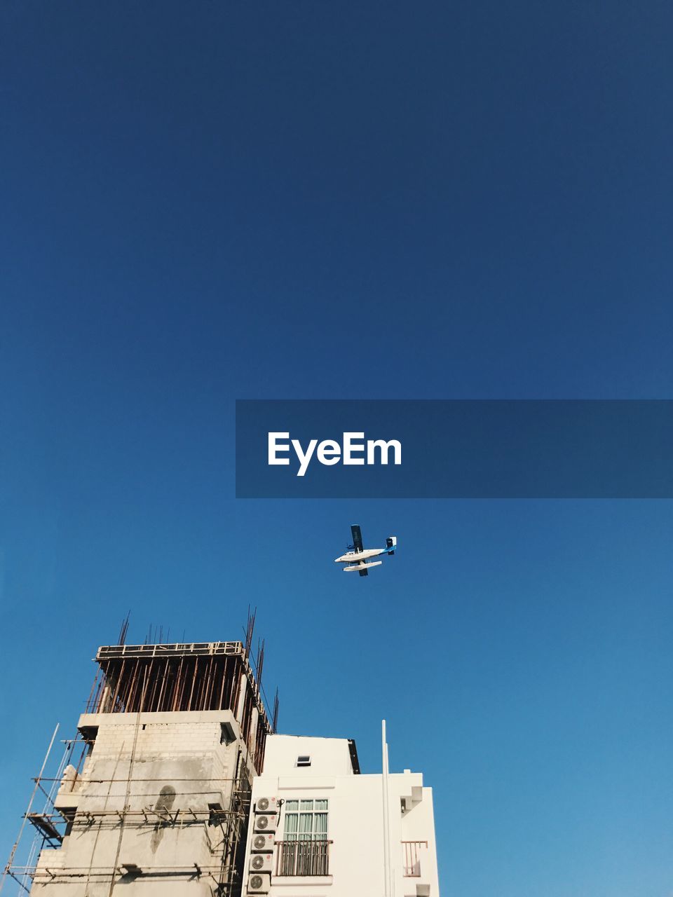 LOW ANGLE VIEW OF AIRPLANE AGAINST CLEAR BLUE SKY