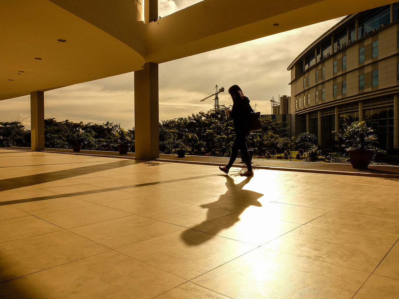 Woman walking in campus by building during sunset