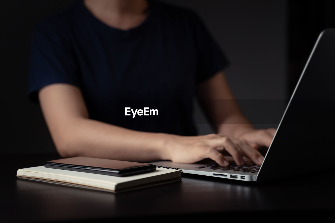MIDSECTION OF MAN USING LAPTOP