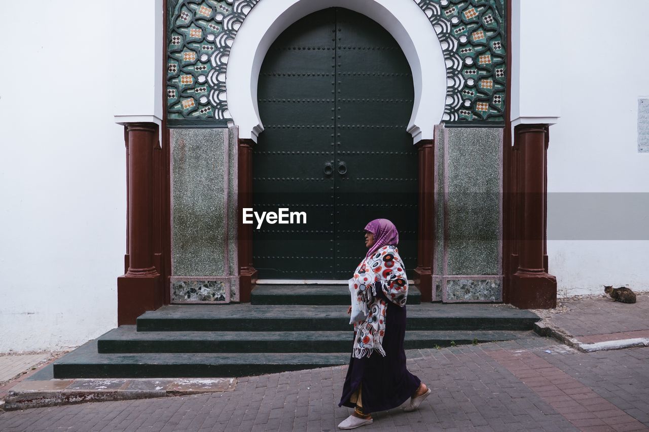 FULL LENGTH OF WOMAN STANDING ON ENTRANCE OF BUILDING