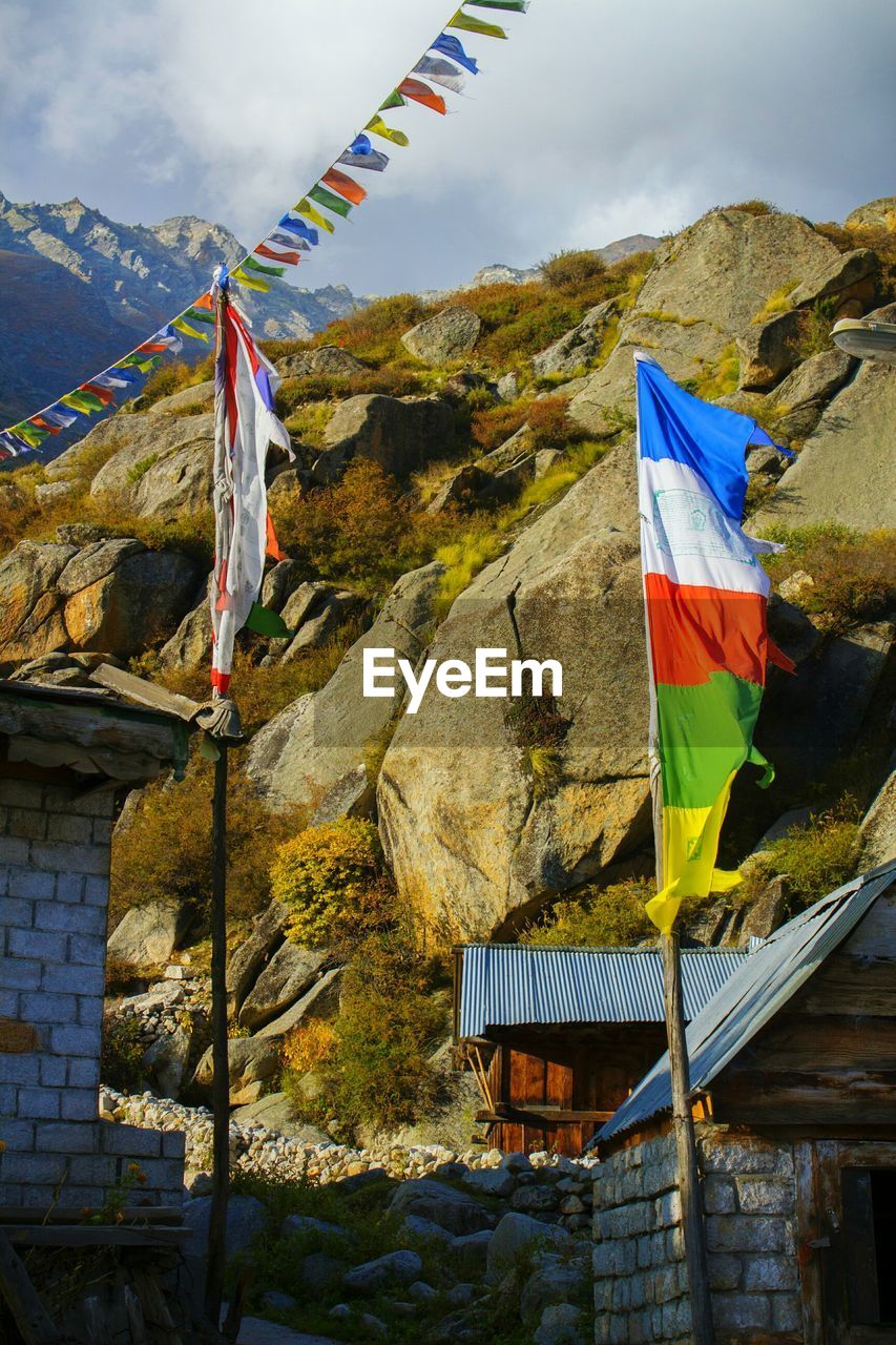 LOW ANGLE VIEW OF FLAGS HANGING ON MOUNTAIN