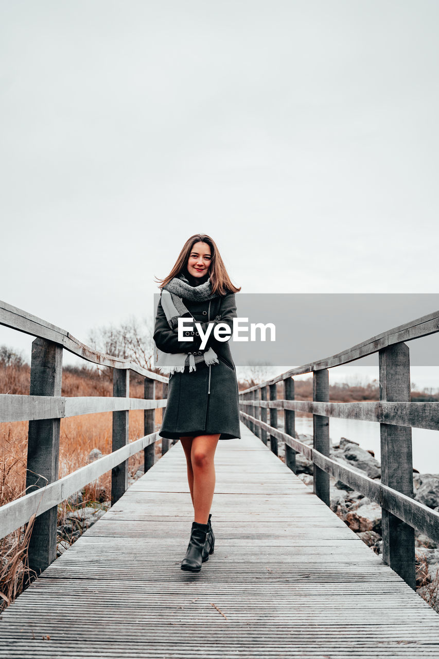 Portrait of young woman with arms crossed walking on footbridge