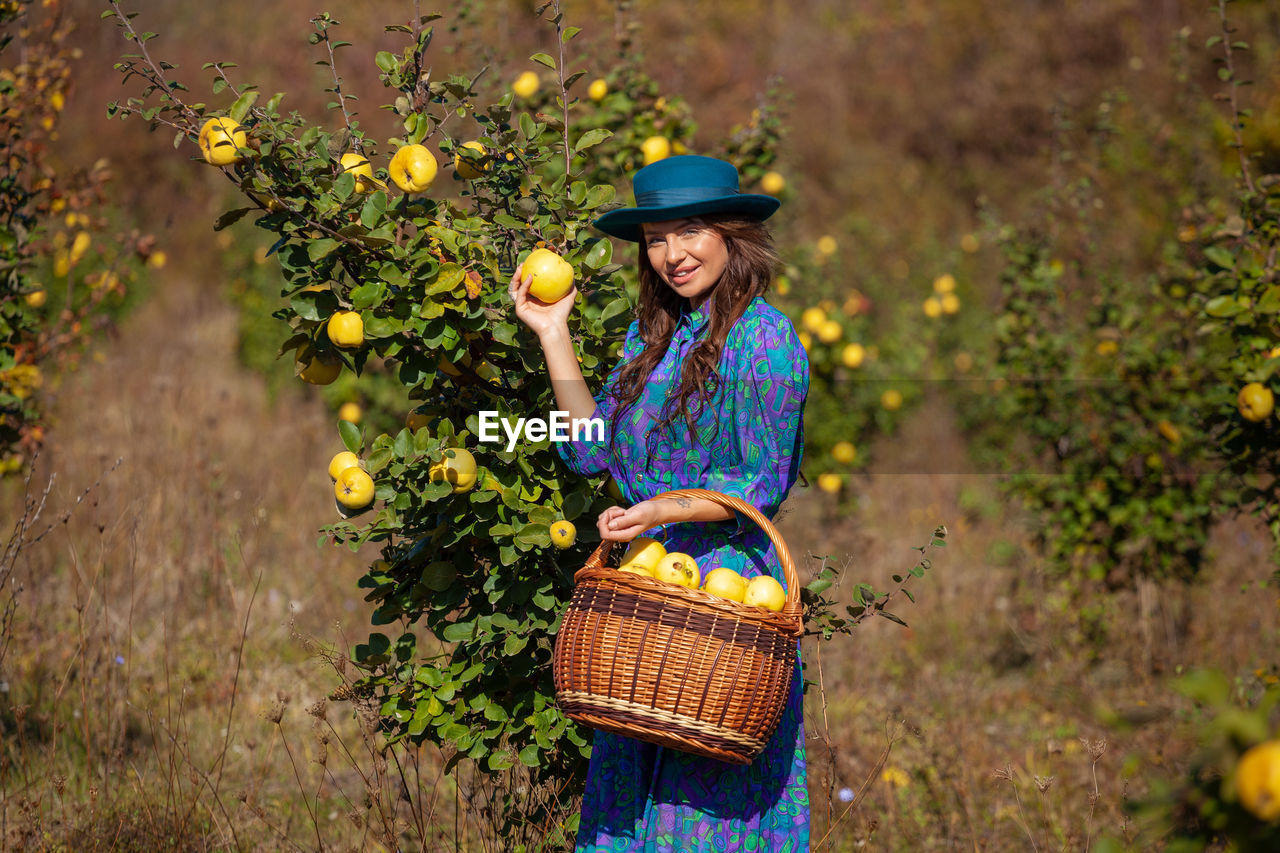 Portrait of woman picking fruits from plants