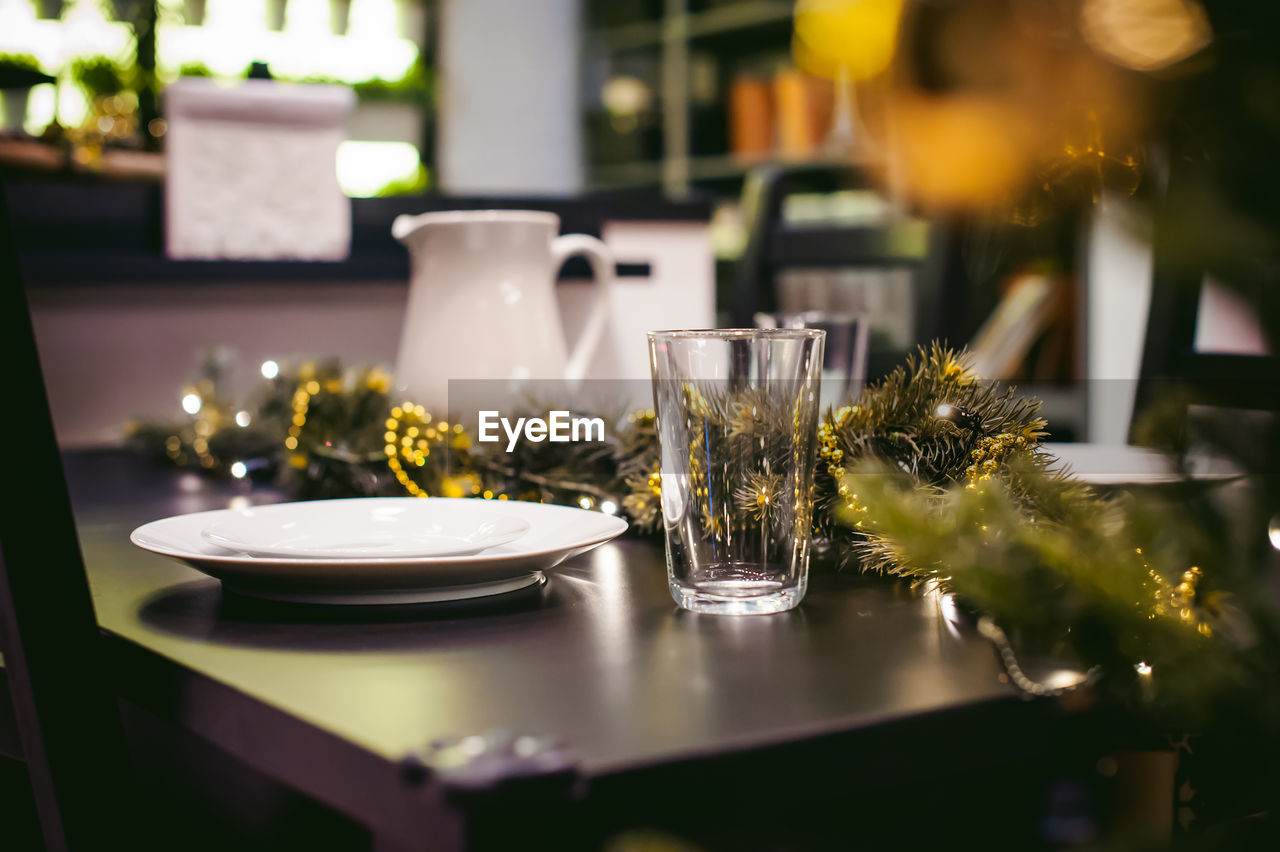 Close-up of plate and drinking glass with christmas decorations on table