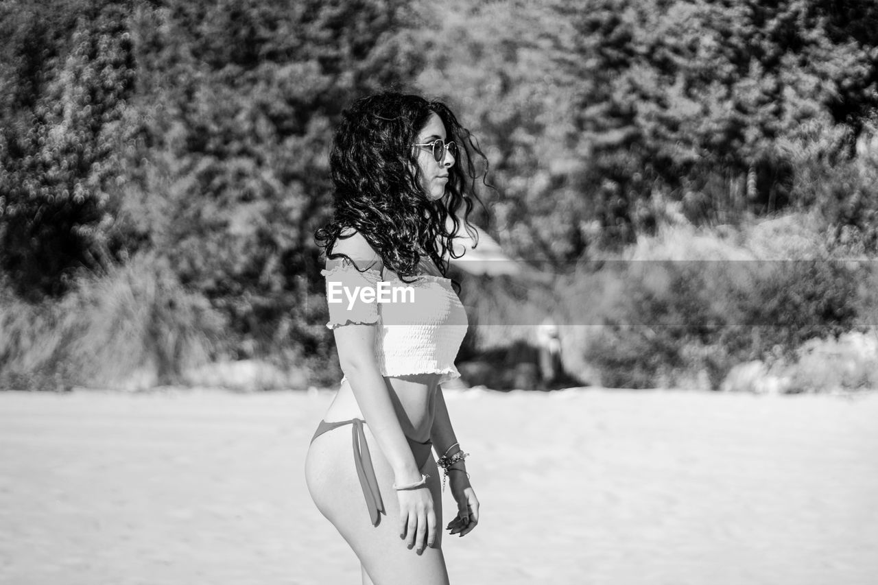 Side view of seductive woman standing at beach during summer