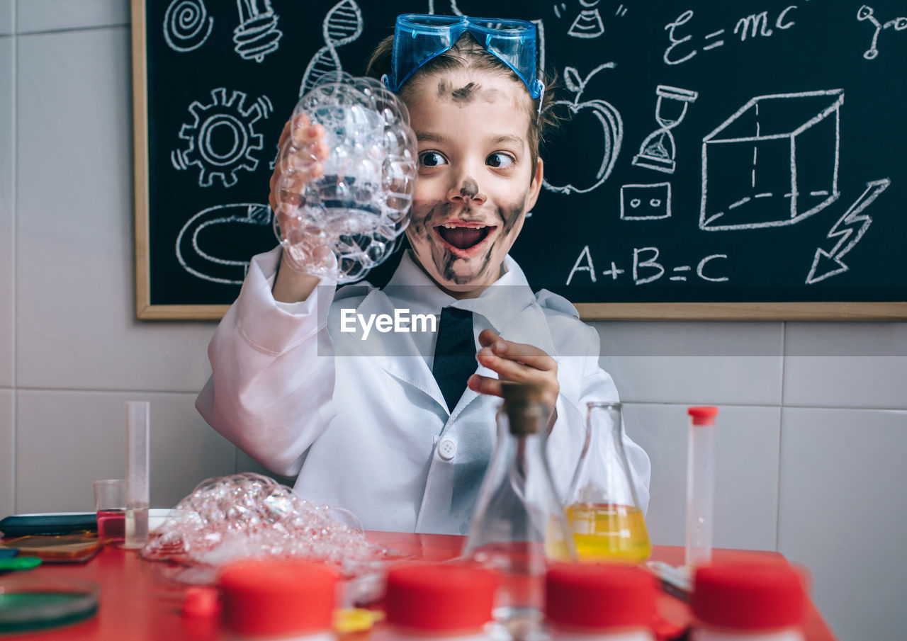 Boy wearing lap coat while standing in classroom