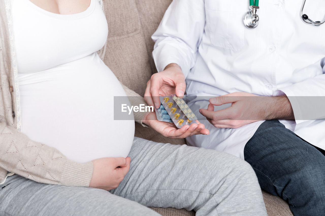 Doctor is giving pills to a pregnant woman and explaining how to use them. treatment 