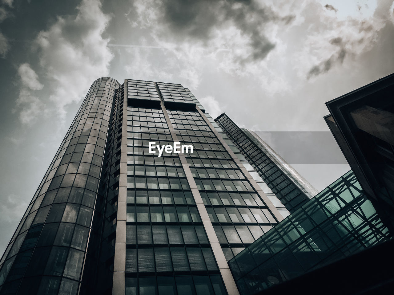 LOW ANGLE VIEW OF MODERN GLASS BUILDING AGAINST SKY