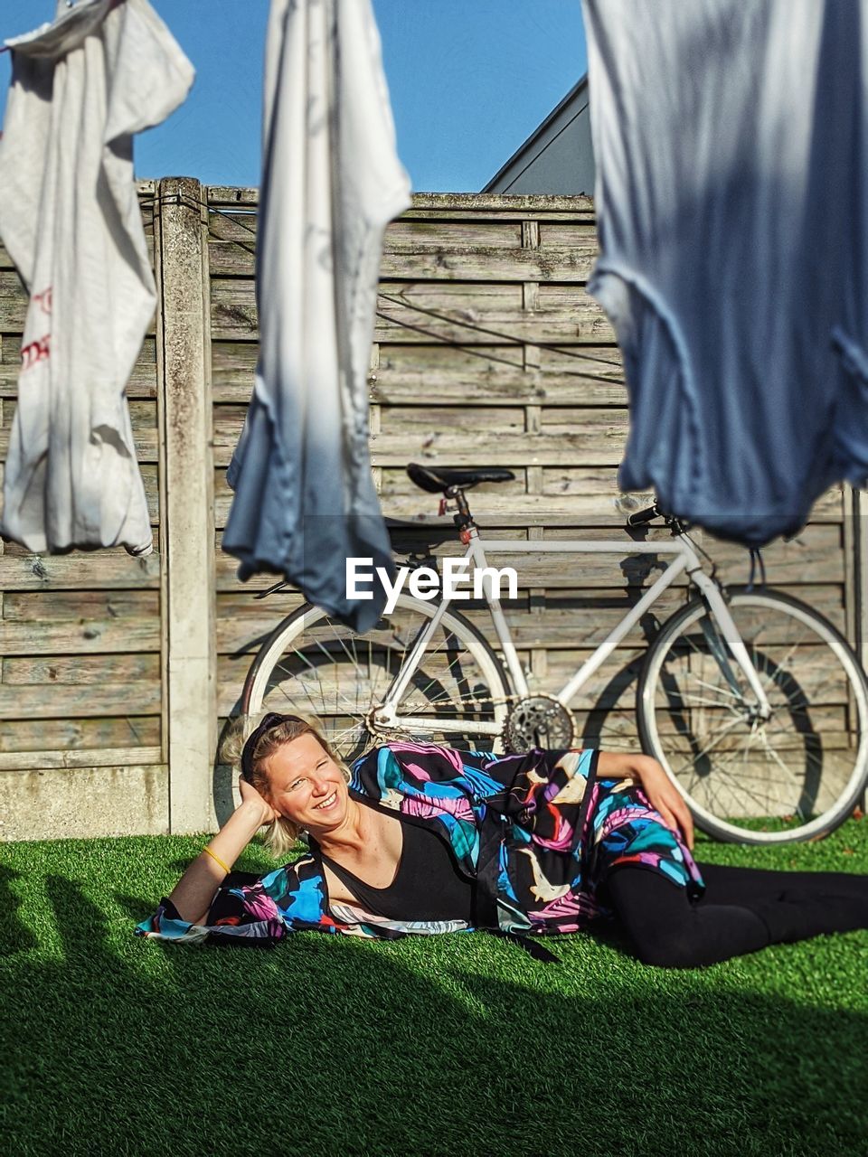 Portrait of smiling woman lying on grass outdoors