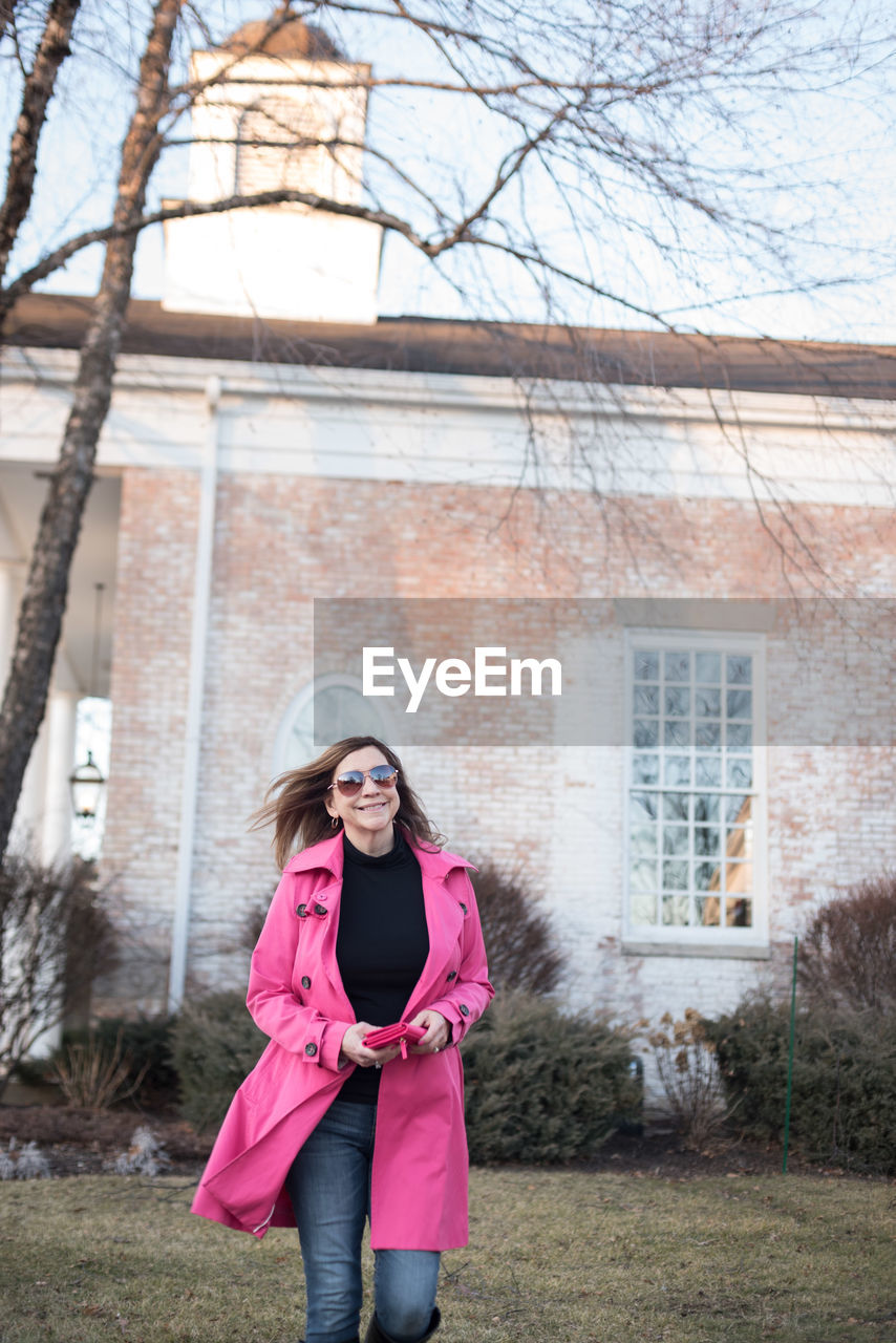 Portrait of woman in sunglasses walking against building