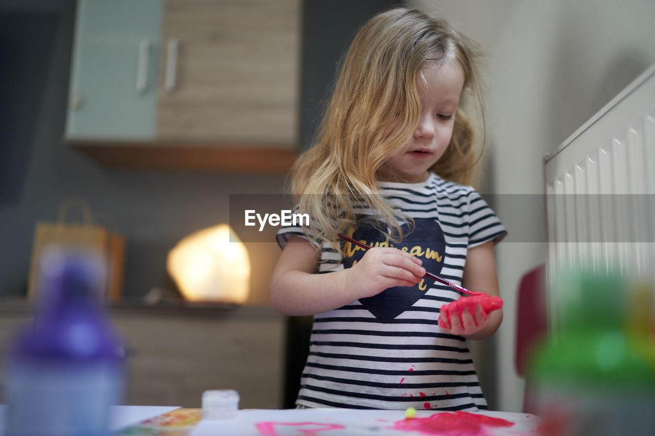 Cute little girl being creative with paint on her palms.