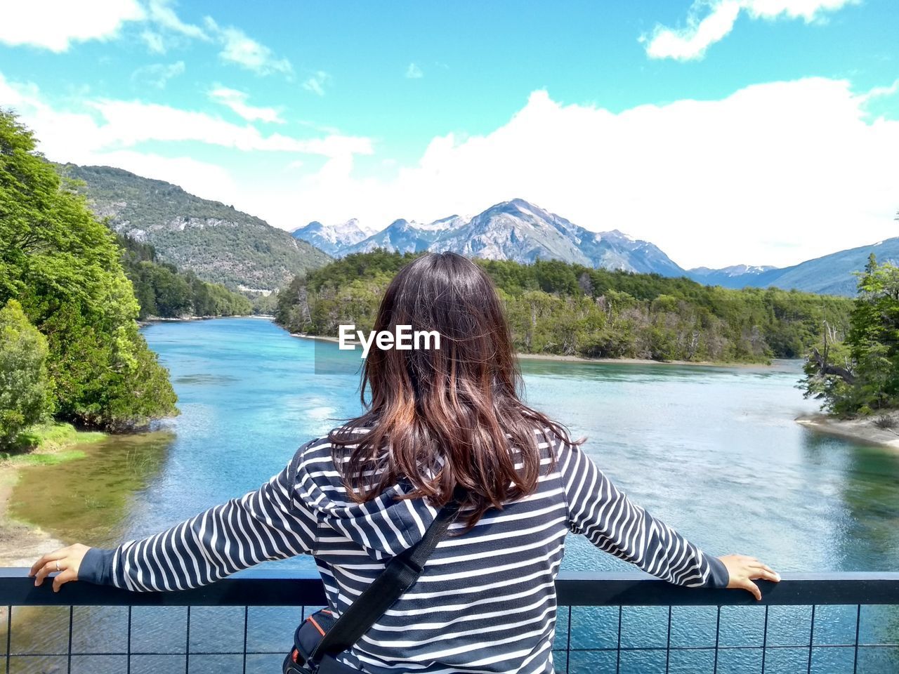 Rear view of woman looking at lake against mountains