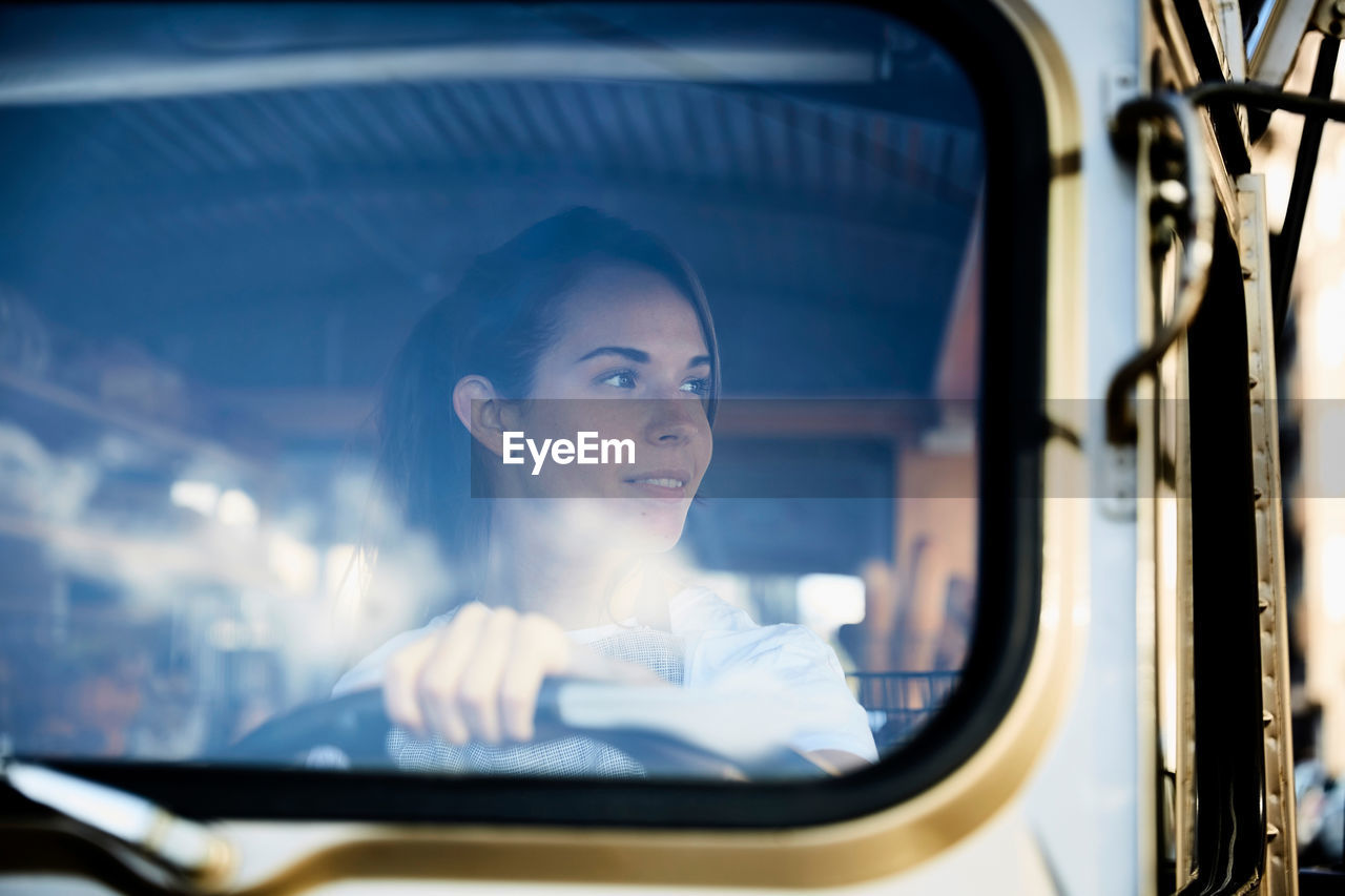 Young saleswoman looking away while driving food truck