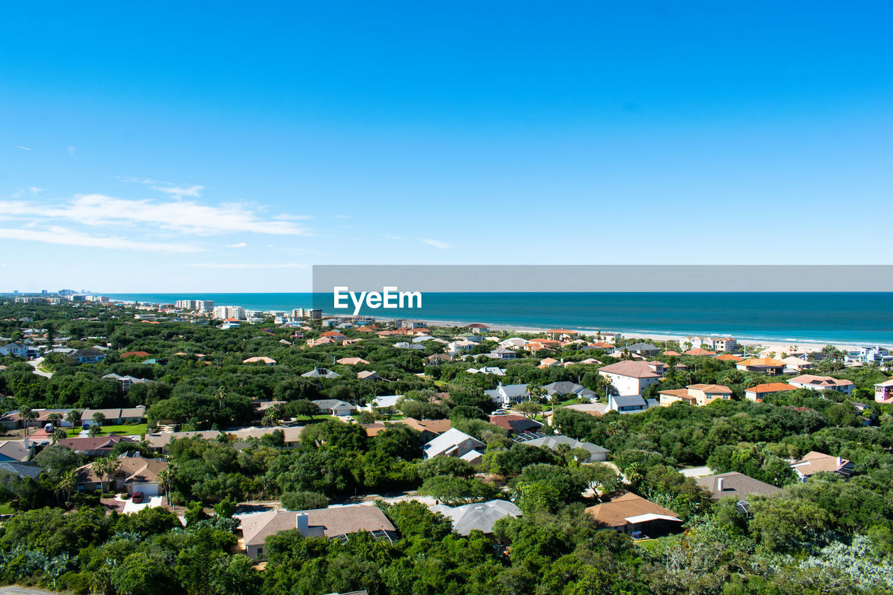 High angle view of buildings and sea against blue sky