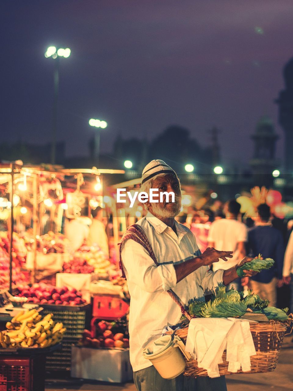 Portrait of vendor selling beetle leaves in illuminated market at night