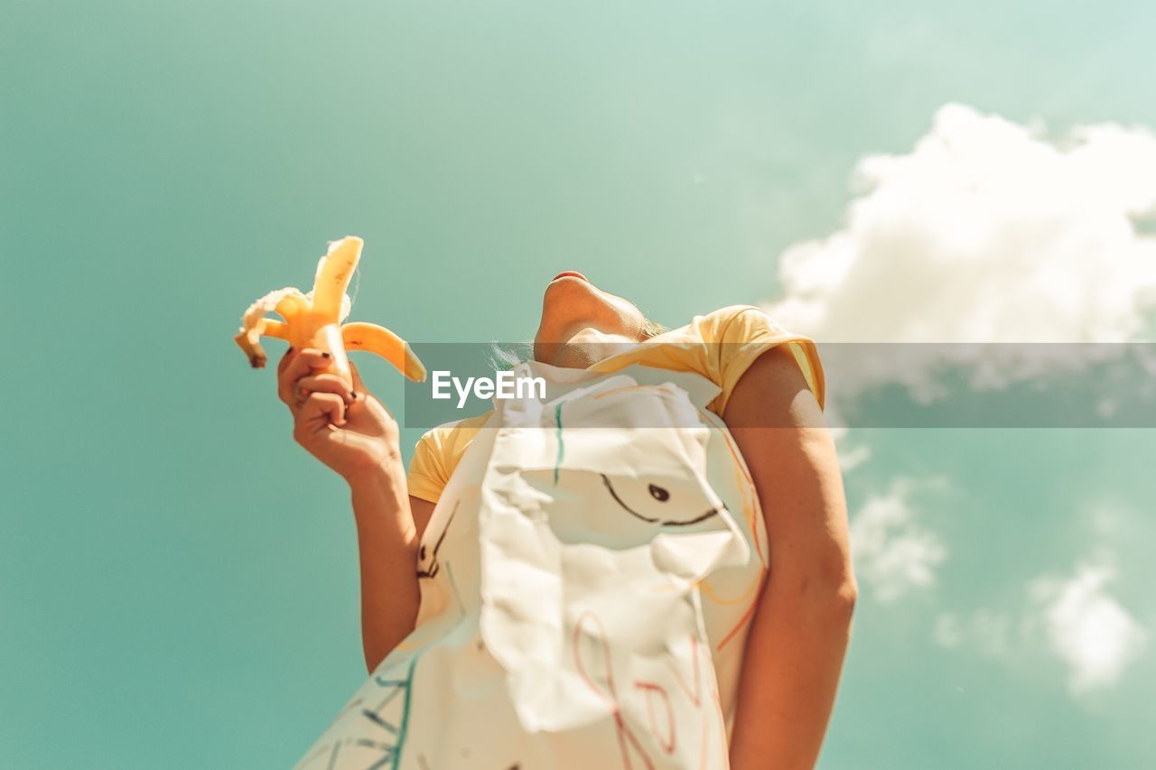 Cropped image of person holding glass jar against sky during sunset