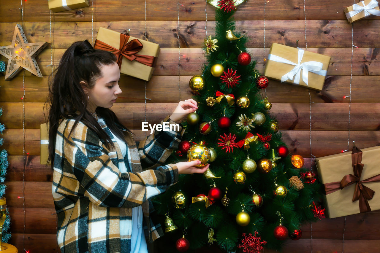 A teenager girl with black hair celebrates christmas in her house. person