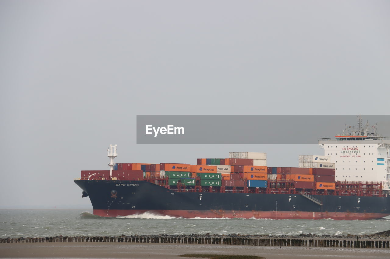 container ship, water, freight transportation, business, transportation, shipping, cargo container, ship, nautical vessel, container, sea, panamax, industry, vehicle, tank ship, architecture, watercraft, trading, mode of transportation, pier, cargo ship, freight transport, bulk carrier, commercial dock, ocean, harbor, unloading, nature, industrial ship, ocean liner, copy space, business finance and industry, oil tanker, sky, loading, carrying, boat, outdoors, no people, beach, machinery, channel, delivering, retail, transport, crane - construction machinery, global business