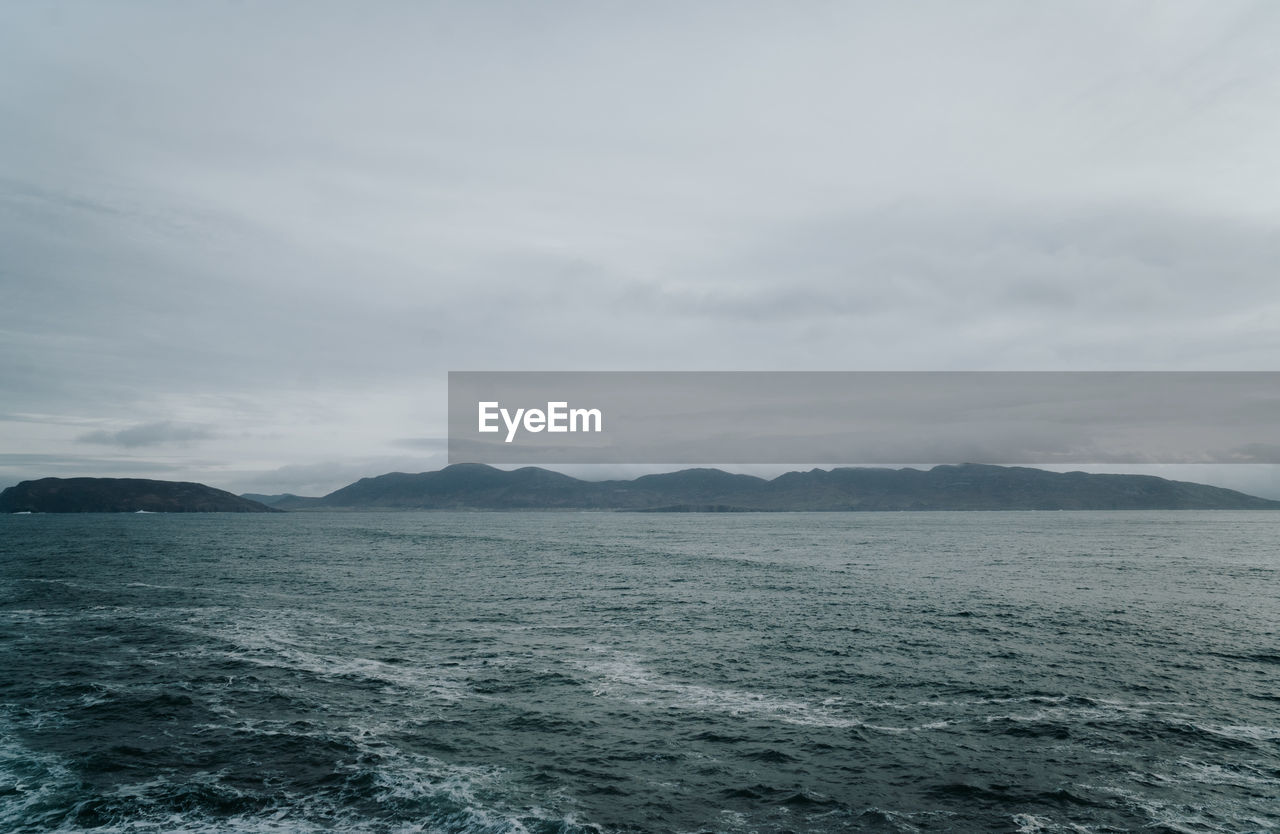 SCENIC VIEW OF SEA AND MOUNTAIN AGAINST SKY