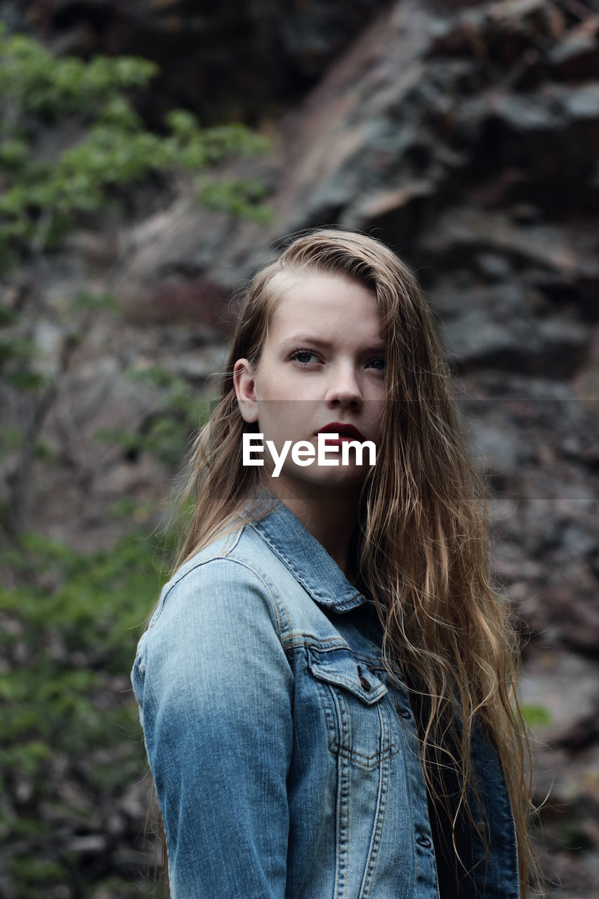 Side view of thoughtful woman looking away while standing against rock formations