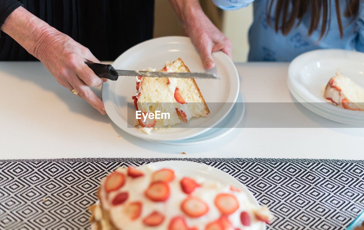 Cropped hands of woman serving sponge cake at table