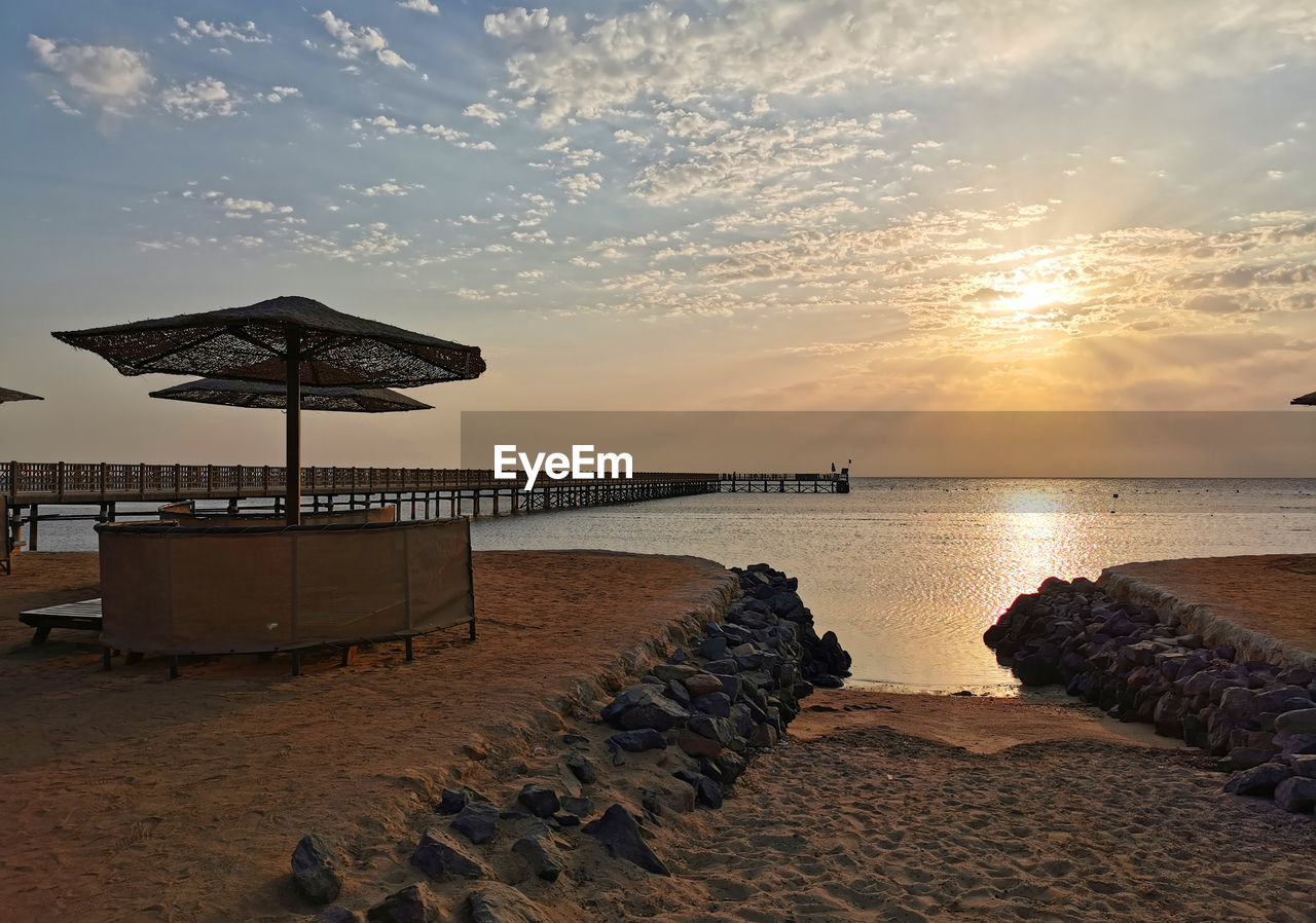 water, sky, sea, beach, land, ocean, sunset, coast, shore, beauty in nature, nature, horizon, scenics - nature, tranquility, sand, horizon over water, cloud, tranquil scene, evening, travel destinations, vacation, architecture, trip, dusk, holiday, body of water, idyllic, sun, coastline, summer, seascape, travel, sunlight, hut, bay, outdoors, chair, no people, relaxation, tourism, built structure, wave, reflection, seat, umbrella