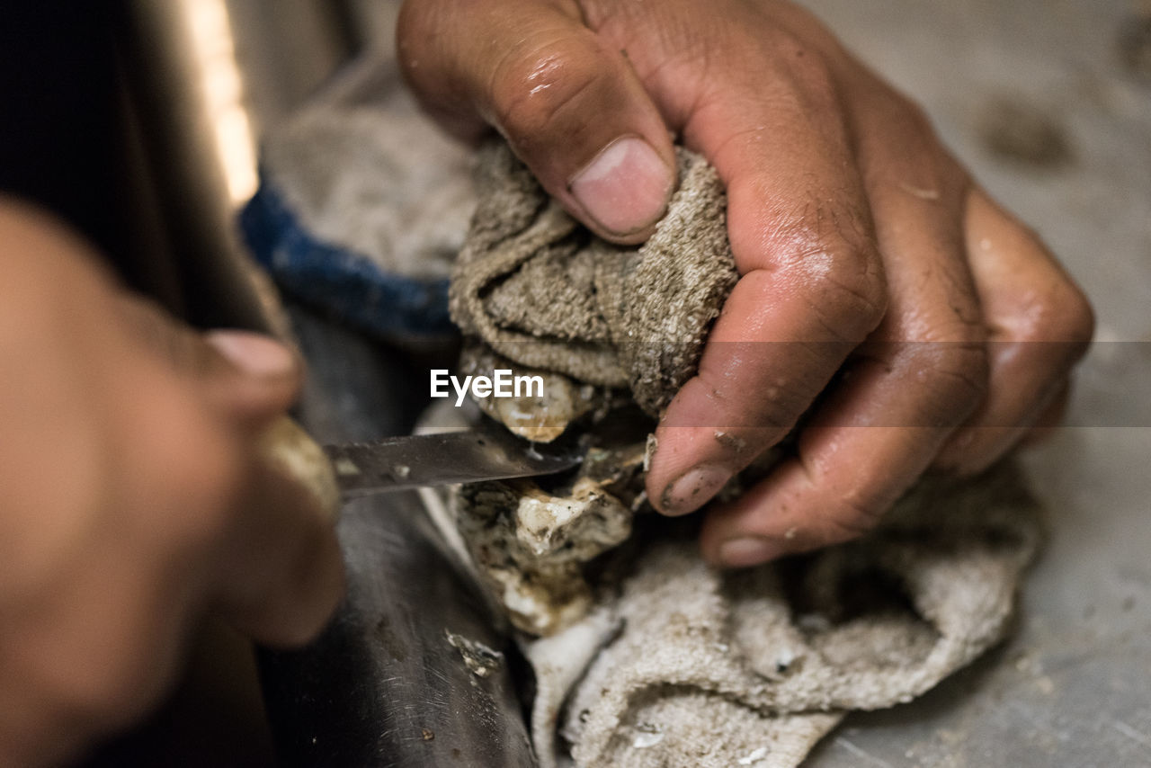 Cropped image of person shucking oyster on table
