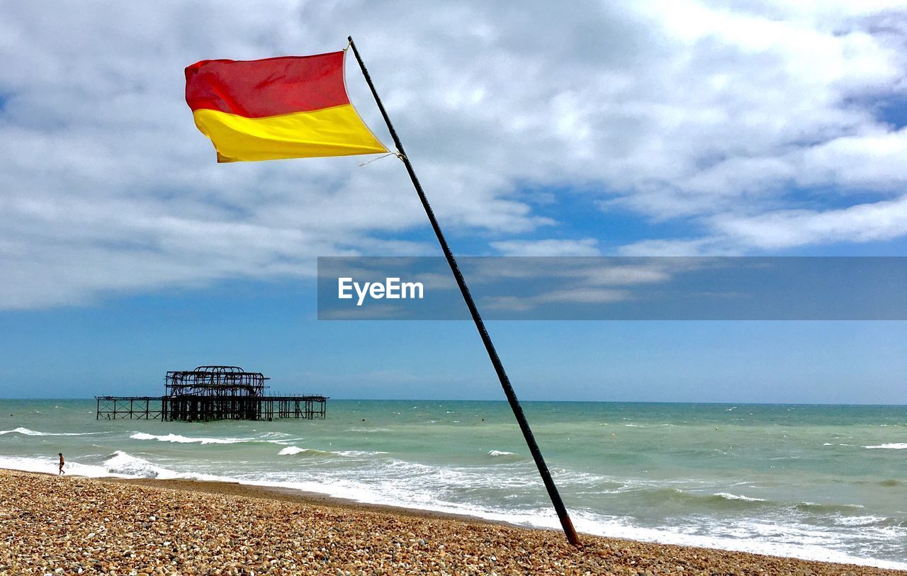 FLAGS ON BEACH AGAINST SKY