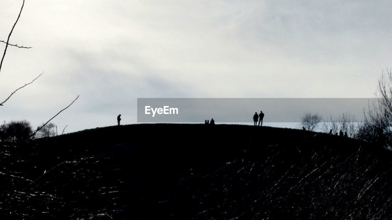 Silhouettes against cloudy sky