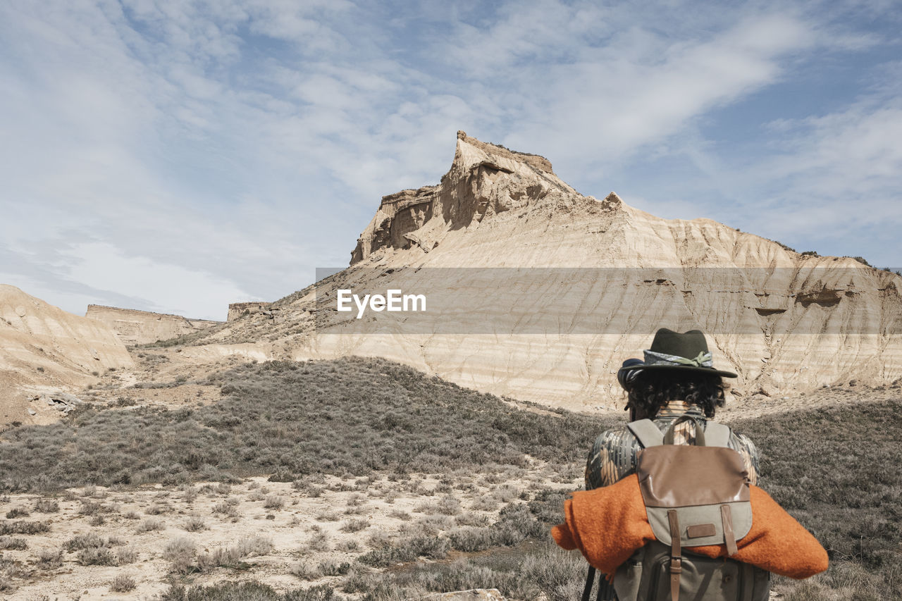 Rear view a traveler taking pictures with a backpack in the bardenas desert. navarre