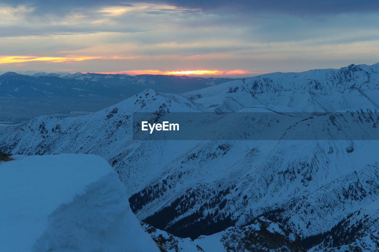SNOW COVERED MOUNTAINS AGAINST SKY DURING SUNSET