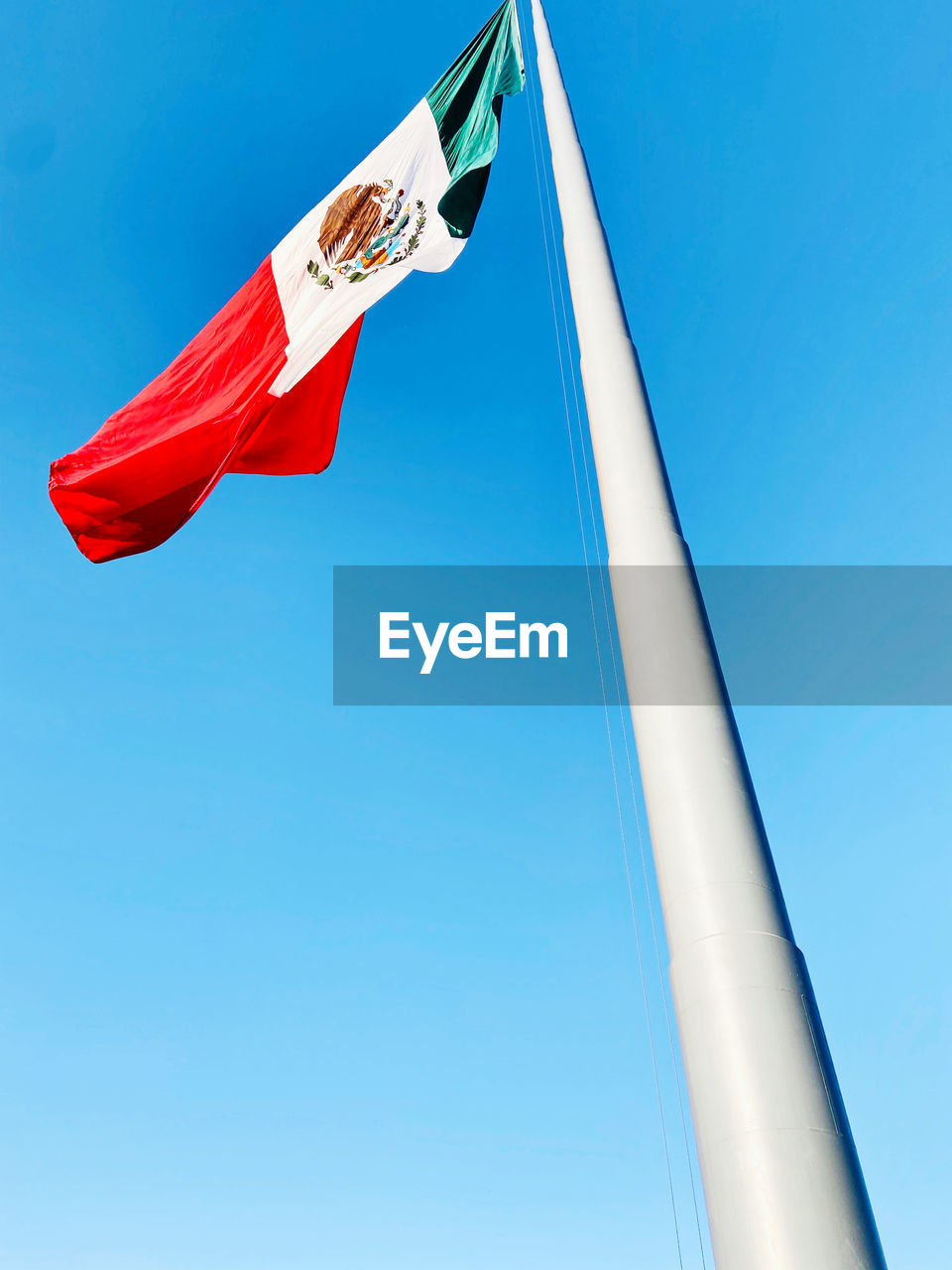 Low angle view of mexican flag against clear blue sky