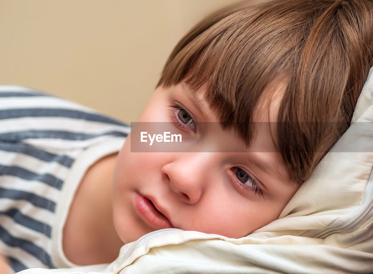 Close-up of cute baby boy lying on bed at home