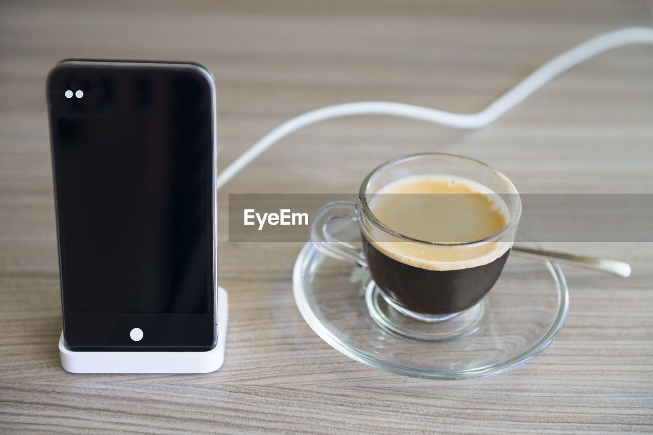 Close-up of coffee cup by smart phone on table