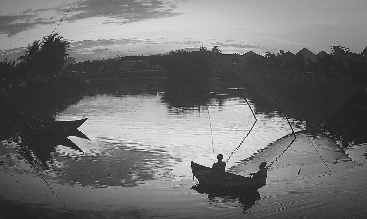 Silhouette boat sailing in river during sunset