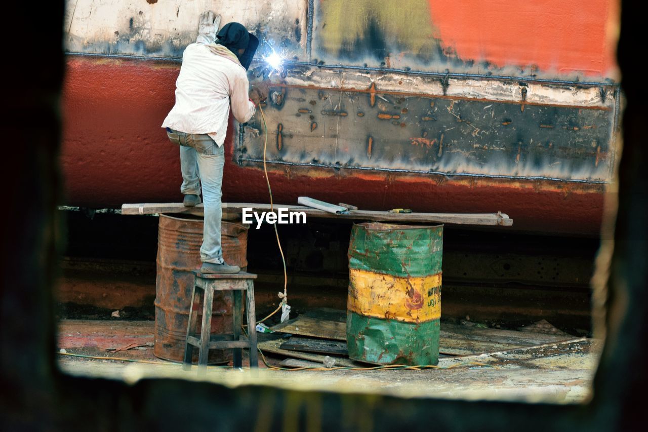 Rear view of man working at shipyard