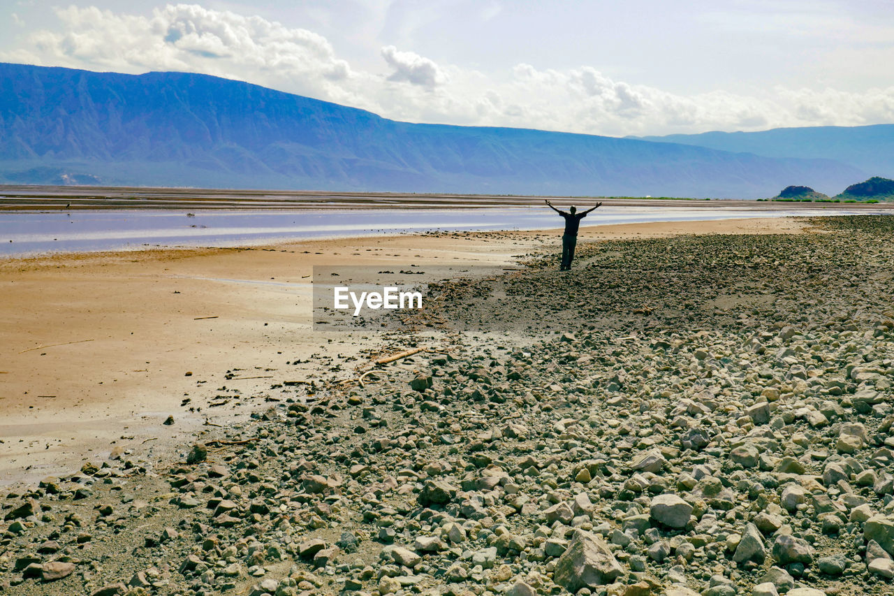 A tourist walking along the shores of lake natron against sky on a sunny day in rural tanzania