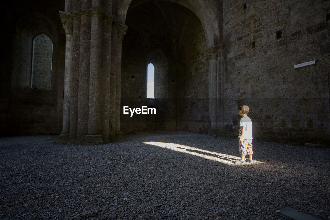 Side view of boy standing at historic building