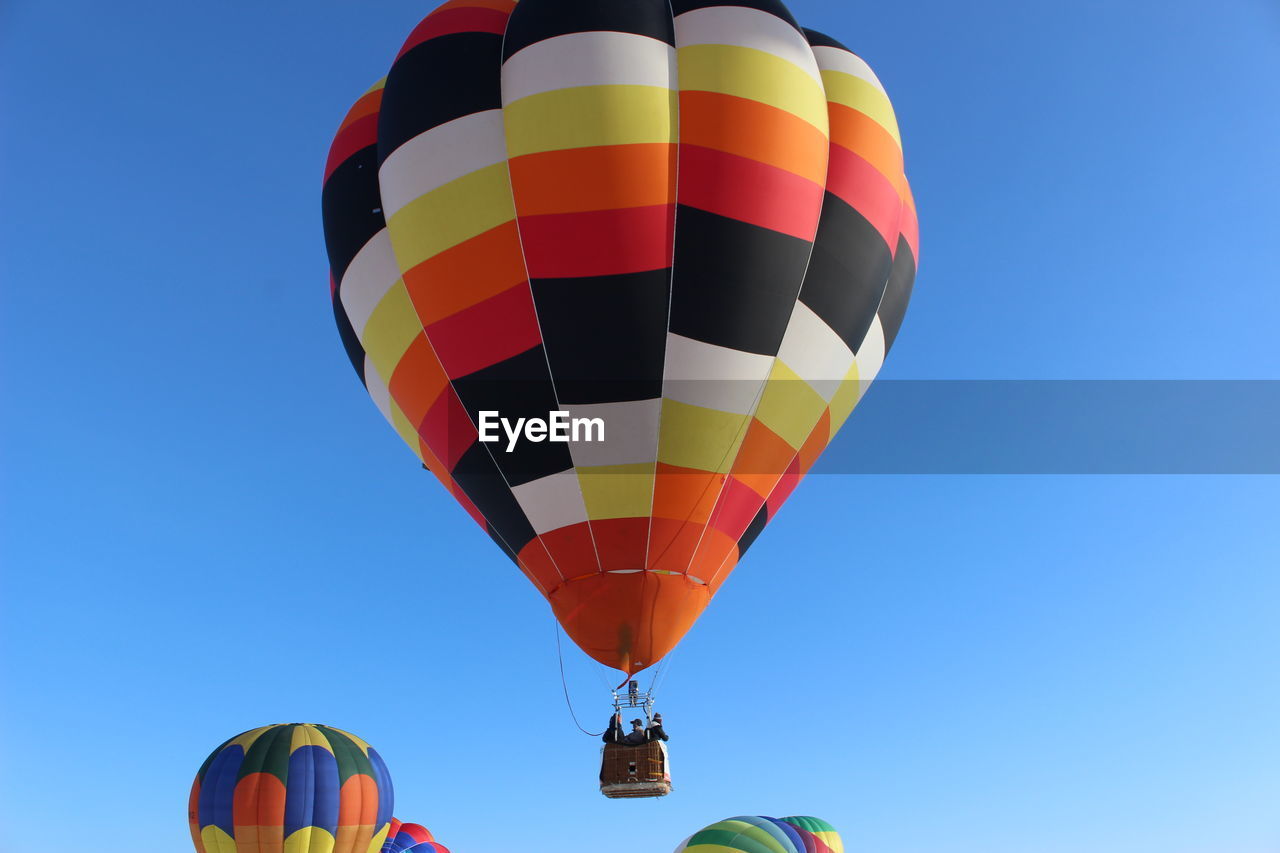 Low angle view of hot air balloons against clear blue sky