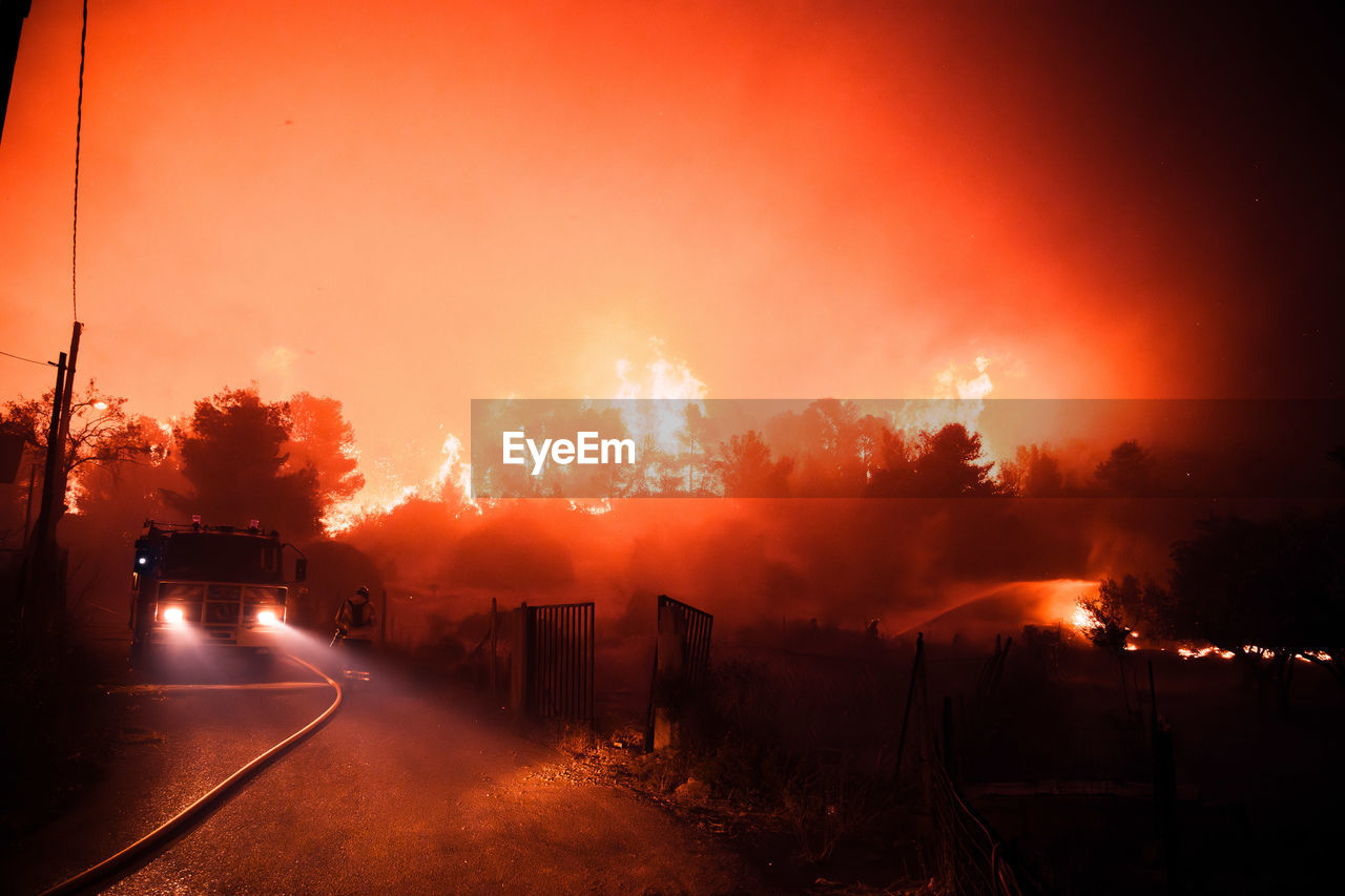 fire, wildfire, transportation, sign, burning, nature, accidents and disasters, warning sign, road, mode of transportation, motor vehicle, no people, environment, car, communication, night, flame, smoke, heat, destruction, morning, city, street, outdoors, orange color, architecture