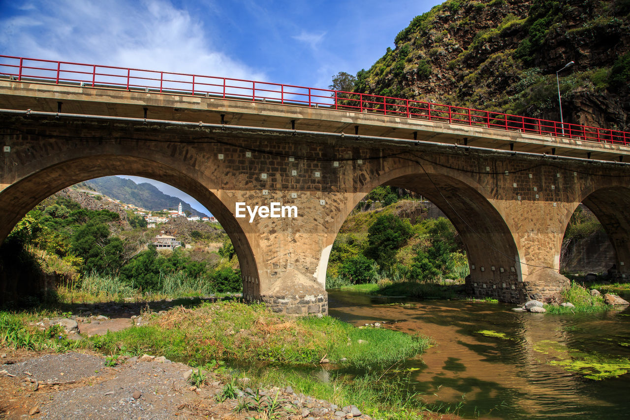 Arch bridge over river against sky