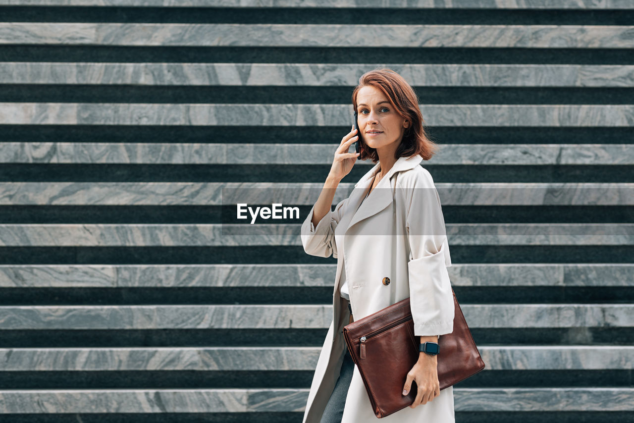 portrait of young woman standing on footpath