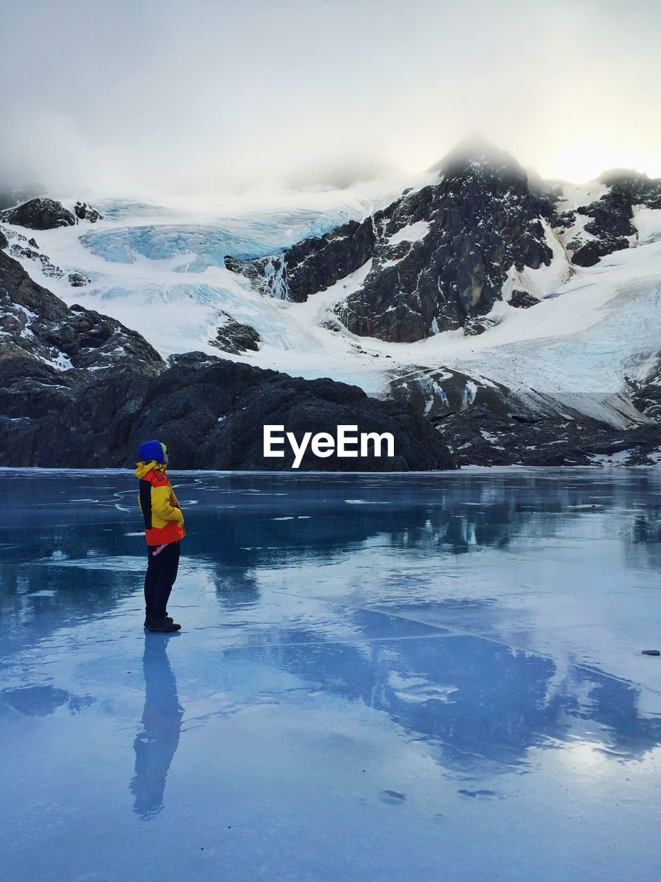 REAR VIEW OF MAN ON SNOW COVERED MOUNTAINS