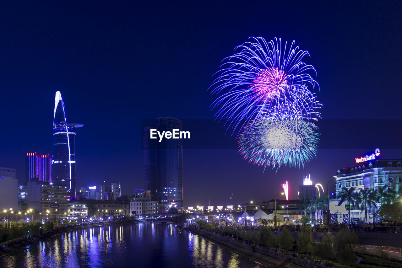 Firework display over river against sky at night