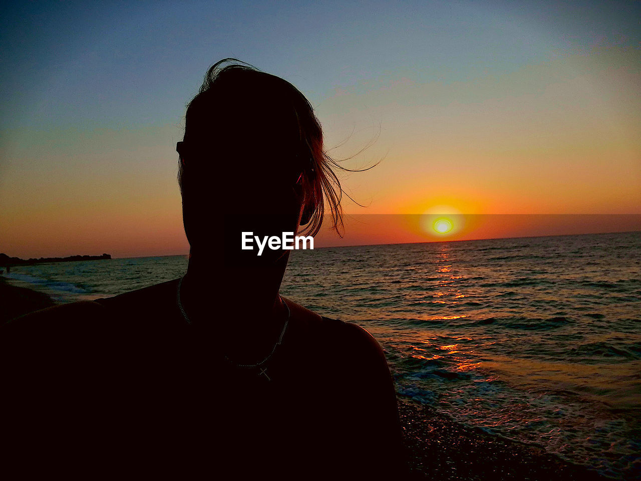 SILHOUETTE WOMAN ON BEACH AGAINST ORANGE SKY