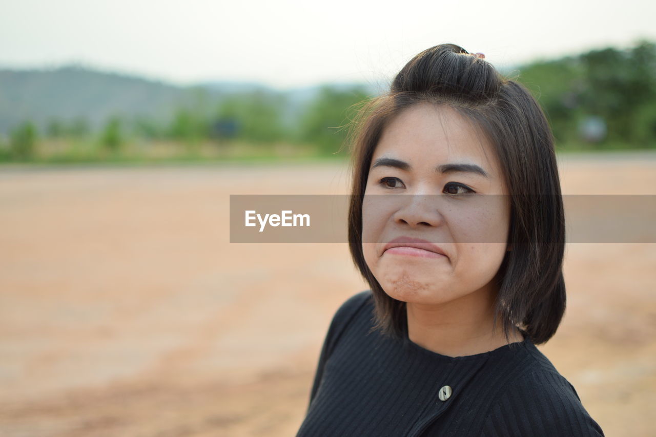 Close-up of beautiful young woman making face on land